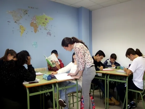 Unha profesora axuda a un grupo de alumnos na aula